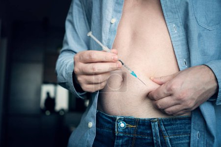 Téléchargez les photos : Jeune homme main utilisant une seringue d'insuline fermer. injection d'insuline à domicile. automédication - en image libre de droit