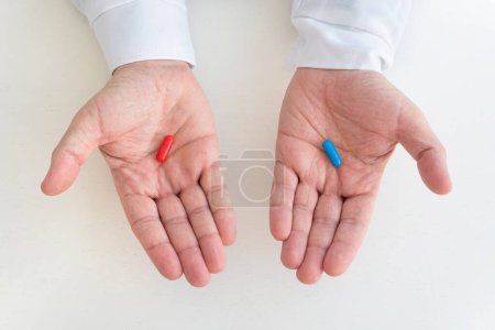 Photo for Hand taking medicine capsule pills on white background. a red and blue pill in a man's hand. The concept of choosing treatment and medicine. - Royalty Free Image