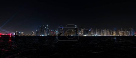 Foto de Panorama nocturno de Dubai Marina. Hermosa vista nocturna de los rascacielos de Dubai desde el mar. - Imagen libre de derechos