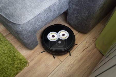 Photo for Automatic robot vacuum cleaner in black on a wooden floor . New modern technologies for apartment cleaning. smart home electronic assistant. robot vacuum cleaner goes around the sofa. home assistant - Royalty Free Image
