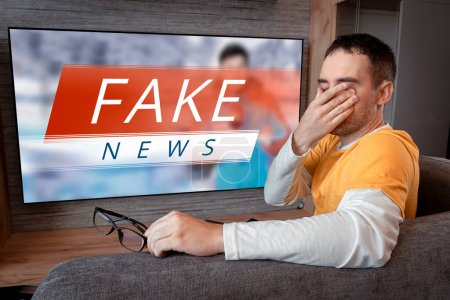 Photo for Lies of tv propaganda mainstream media disinformation, A fake news report. viewer is watching TV and doesn't believe in fake news. man closes his eyes not to watch the lies on TV - Royalty Free Image