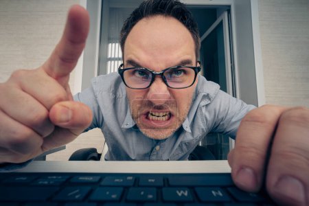 Photo for Angry hayter writes negative comments on the social network. Negative emotions of a businessman employee in front of a computer. malice and hatred concept. offended nerd reads the message on website. - Royalty Free Image