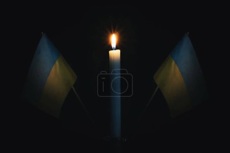 Téléchargez les photos : Le deuil à la campagne. Une bougie allumée sur le fond du drapeau ukrainien. Victimes du cataclysme ou concept de guerre. jour du Souvenir, jour du Souvenir. Le deuil national. - en image libre de droit