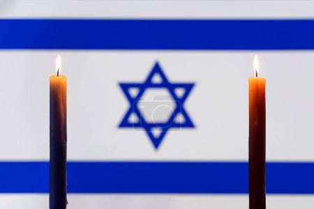 Photo for Mourning in the country. A burning candle on the background of the israel flag. Victims of cataclysm or war concept. memorial day, remembrance day. National mourning. - Royalty Free Image