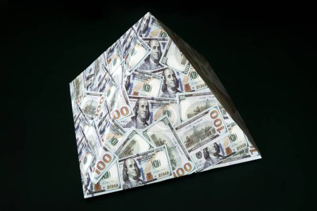 Téléchargez les photos : Un schéma pyramidal sur fond noir. Le concept de fraude financière. Le dollar comme pyramide financière mondiale. - en image libre de droit