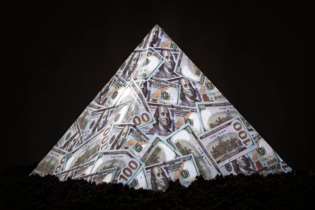 Téléchargez les photos : Un schéma pyramidal sur fond noir. Le concept de fraude financière. Le dollar comme pyramide financière mondiale. - en image libre de droit