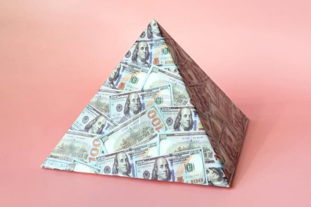 Photo for A pyramid scheme isolated on a pink background. The concept of exchange in financial markets is the collapse of the financial system of capitalism. - Royalty Free Image