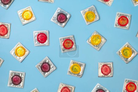 Foto de Vista superior Preservativos coloridos en un paquete sobre un fondo azul. - Imagen libre de derechos