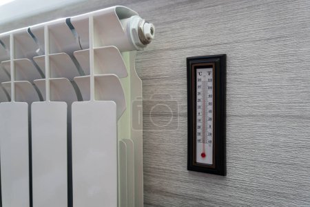 Téléchargez les photos : Thermomètre de radiateur de chauffage réglé à basse température et thermomètre ambiant pour économiser de l'argent aux coûts de chauffage. Crise énergétique, efficacité énergétique et hausse des coûts de chauffage en Europe - en image libre de droit