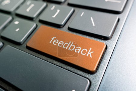 press orange feedback button on laptop keyboard. feedback inscriptions on the keyboard button close up-stock-photo