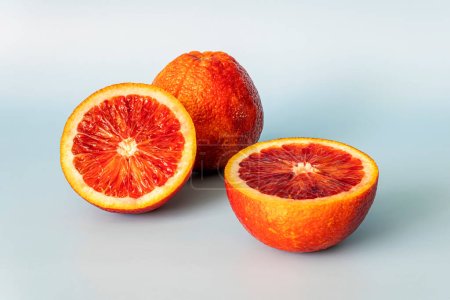 Die Hälfte der blutroten, orangen Zitrusfrüchte auf blauem Hintergrund. rote orangefarbene Hälfte mit Schneideweg