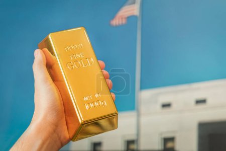 Téléchargez les photos : Un lingot d'or dans la main d'un homme sur le fond de la voûte d'or de l'Amérique. - en image libre de droit