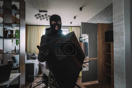 Photo for Marauder takes the TV out of an empty apartment. Apartment theft concept. The burglar. - Royalty Free Image