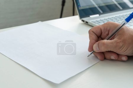 Foto de Una mano con un bolígrafo en primer plano muestra un documento de papel vacío. Un hombre llena un formulario de papel blanco con un bolígrafo en primer plano a la luz del sol. - Imagen libre de derechos
