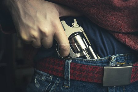 street crime concept. a man robs on the street. The search of the criminal, the man pulls a gun out of his jeans. Death threat. Personal weapons for self-defense.