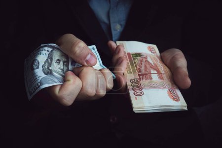 Photo for The ban on the use of the dollar in Russia. a man holds American dollars and Russian rubles in his hands. The concept of choosing a currency for international settlements. prohibition of use dollar - Royalty Free Image