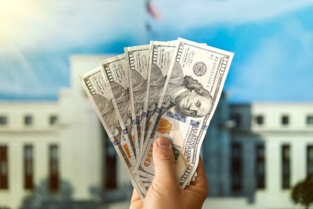 Téléchargez les photos : Dollars dans la main d'un homme sur le fond Federal Reserve Building à Washington DC, États-Unis, FED - en image libre de droit