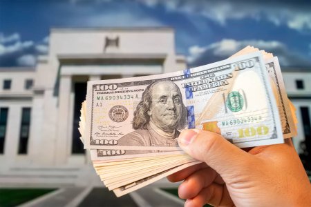 Dollar in der Hand eines Mannes im Hintergrund Federal Reserve Building in Washington DC, USA, FED