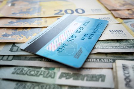 Photo for Payment card on background of paper dollars. blue plastic multicurrency credit card is lying on a stack of money euros rubles and dollars - Royalty Free Image