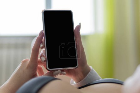Photo for Close-up image of female hands holding a smartphone. Sexy light-skinned woman with big Breasts. Seductive communication, candid cleavage. Online addiction, Dating, chat. woman at home watching video - Royalty Free Image