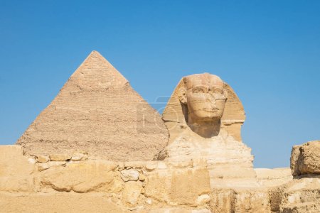 Téléchargez les photos : Gros plan du visage du Grand Sphinx avec pyramide en arrière-plan sur une belle journée de ciel bleu à Gizeh, Le Caire, Egypte. espace de copie - en image libre de droit
