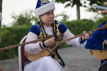 Téléchargez les photos : Femme kazakhe en costume bleu jouant de la dombra Instrument de musique kazakh, Almaty, Kazakhstan. 25 mai 2023 - en image libre de droit