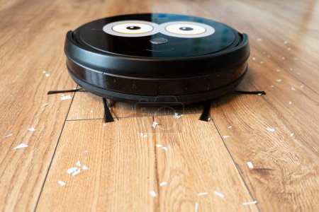 Photo for Robotic vacuum cleaner on laminate wood floor smart cleaning technology. - Royalty Free Image