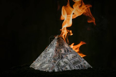Photo for The concept of exchange in financial markets is the collapse of the financial system of capitalism. collapse of a financial pyramid, dollars are burning in the dark. - Royalty Free Image