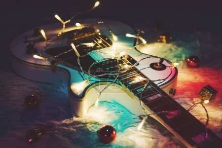 Téléchargez les photos : Guitare avec jouets de Noël décoré Noël. Guitare classique blanche dans l'éblouissement des lumières vives. Cadeau musical pour le rocker
. - en image libre de droit