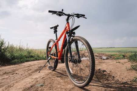 Photo for Orange mountain sports bike on a muddy country road in a field. Off-road driving after the rain. - Royalty Free Image