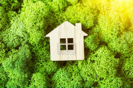 Photo for A small toy house on a background of plants as a symbol of a private country house. The concept of real estate in mortgages. sunlight - Royalty Free Image