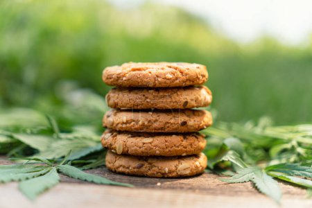 Photo for Marijuana leaf and sweets on wooden table. Cannabis flowers and cookies close up. Hemp recreation, canna kitchen, pastime, legalization concept. cookies with cannabis seeds on a wooden table - Royalty Free Image