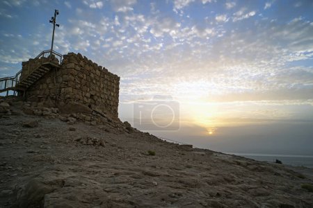 Photo for The tallest tower of Masada against the cloudy sky at dawn in the sun. Historical excavations on the ruins of the ancient era. Israel - Royalty Free Image