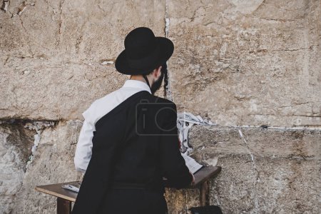 Foto de Joven judío religioso de pie contra el Muro de los Lamentos con el libro sagrado y la oración. Jerusalén, Israel: 24 de octubre de 2018 - Imagen libre de derechos
