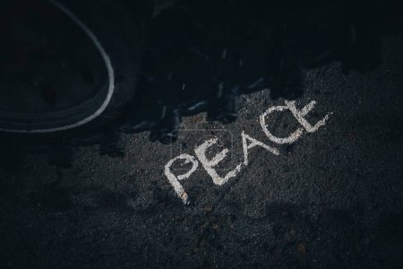 Photo for Tank runs over the pacificus sign. Destruction of the world concept the liquidation of peace on earth. the word peace is drawn in chalk on asphalt in front of the tank tracks - Royalty Free Image