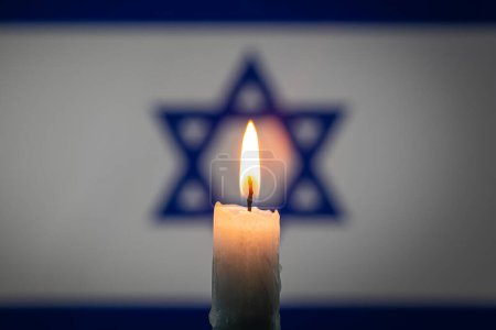 Mourning in country Israel. A burning candle on the background of the Israeli flag. Victims of cataclysm or war concept. Holocaust Memorial Day, remembrance day. National mourning. war in Middle East