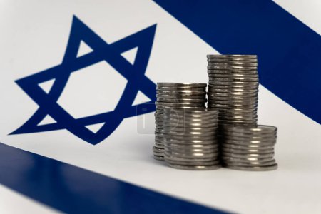 Téléchargez les photos : Piles de pièces sur le fond du drapeau israélien - en image libre de droit