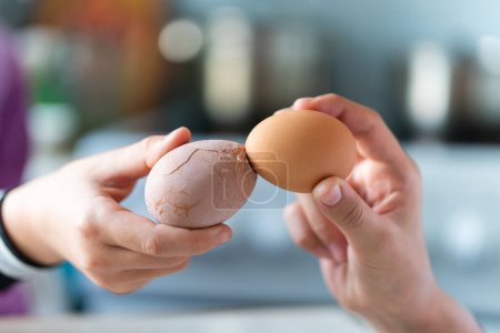 Ostertradition: Eier knacken, zwei Hände halten Eier und versuchen, sich gegenseitig das Ei zu brechen, aus nächster Nähe vor blauem Hintergrund