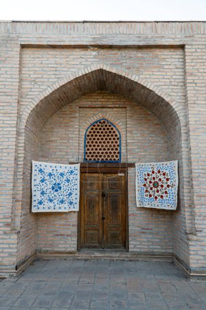 Photo for Small carpets hang on the wall in front of the entrance to the souvenir shop in Samarkand, Uzbekistan. - Royalty Free Image