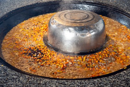 Pilaf chaud dans un grand chaudron à l'extérieur. Nourriture orientale traditionnelle. Concept de nourriture de rue. Gros plan