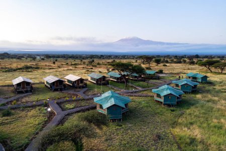 Blick von oben auf ein Zeltlager in der afrikanischen Savanne. Zelte auf dem Hintergrund des Kilimandscharo im Wald in Afrika. Luftbild.