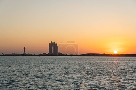 Blick auf die Skyline von Abu Dhabi bei Sonnenuntergang, Sonnenuntergang am Meer in den Vereinigten Arabischen Emiraten