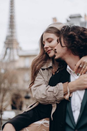 Téléchargez les photos : Un couple amoureux se promène dans les rues de Paris, un mec en manteau et costume, une fille en robe avec un béret et un trench coat en automne - en image libre de droit