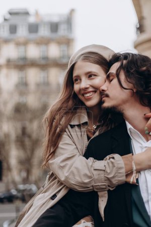 Foto de Una pareja enamorada camina por las calles de París, un tipo con abrigo y traje, una chica con vestido con boina y abrigo en otoño - Imagen libre de derechos