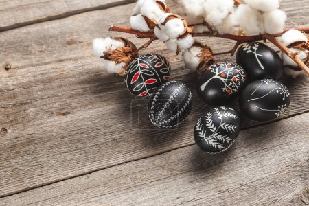 Black and White Pysanka Easter Eggs Decorated with Traditional Eastern European Beeswax Technique and a Branch of Cotton Flower. Greeting Card with Space for Text