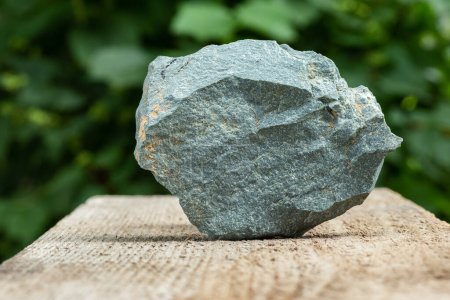 Téléchargez les photos : A Piece of Gray, Slate Metamorphic Rock Sample on Wooden Background - en image libre de droit