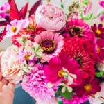 Top view of bouquet of pink rose dahlia zinnia flowers. Interior and summer decor at home. Woman enjoys fresh blooms. Close up of floral arrangement