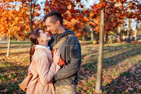 Photo for Young man soldier in military uniform and his wife walking in autumn park. Couple hugging after long separation outdoors. Homecoming - Royalty Free Image