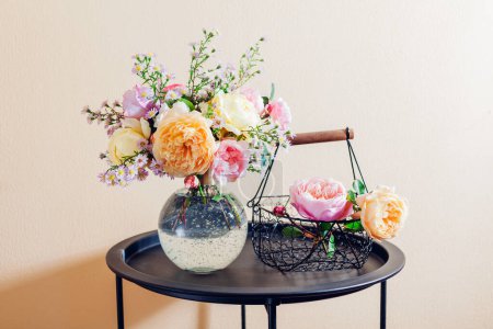 Téléchargez les photos : Bouquet frais de fleurs de roses mis dans un vase en verre sur la table. Gros plan de fleurs jaunes roses avec panier. Décor intérieur d'été - en image libre de droit