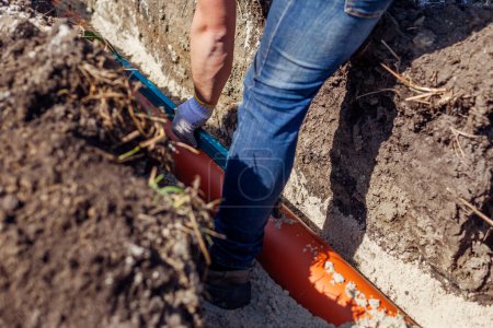 Photo for Plumber measuring slope of assembled sewage pipes using spirit level in trench. Building house. Worker checking pipeline - Royalty Free Image